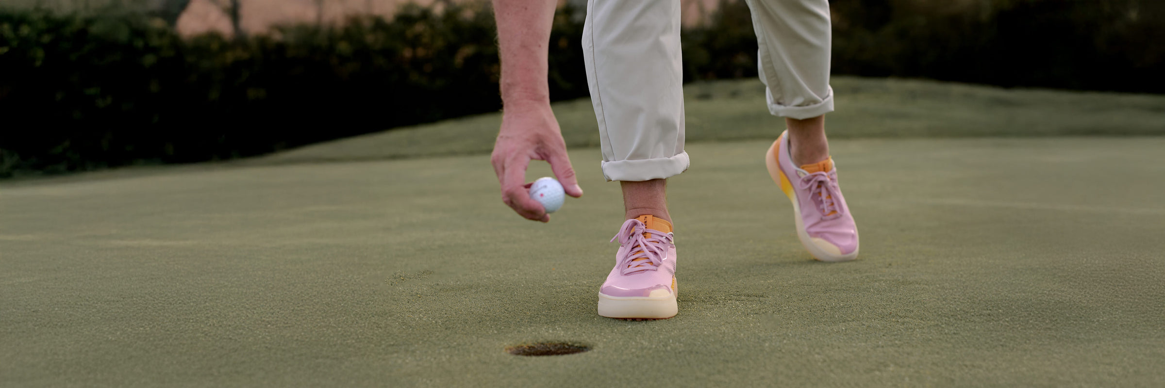 Man wearing Beta Lite shoes in Lavender and Orange on a putting green.