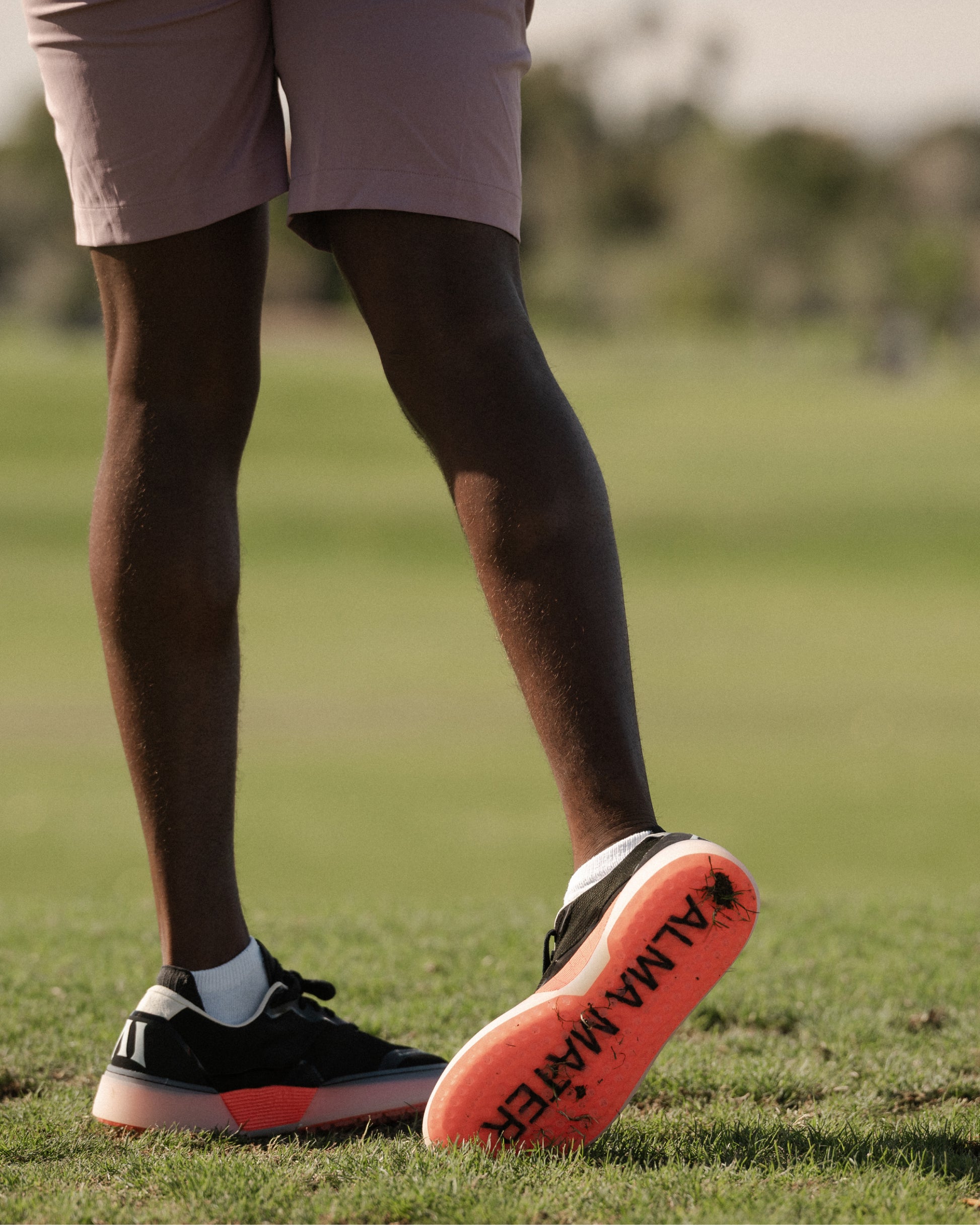Person walking on a golf course wearing black and flare Beta Lite golf shoes with outsole visible