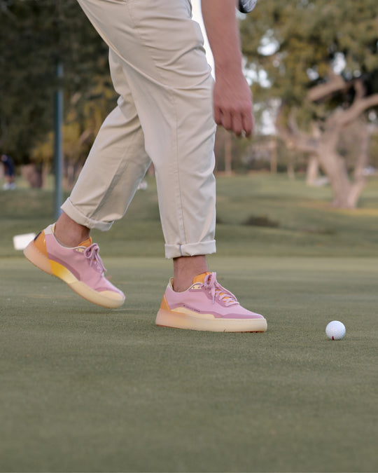 Person wearing Lavender-Orange Beta Lite shoes on a golf course with a blurred background