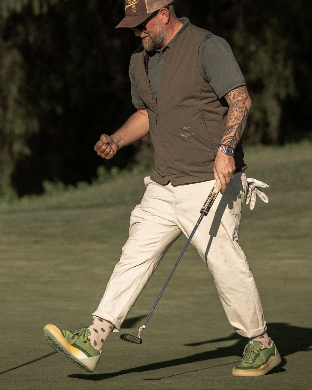 Man walking on a golf course holding a golf club wearing Beta Lite Olive Aqua golf shoes