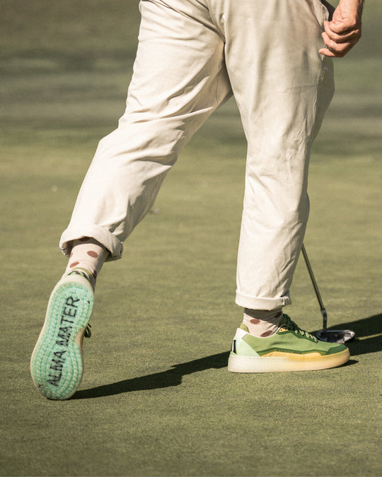 Person wearing light-colored pants and green and Aqua shoes on a golf course