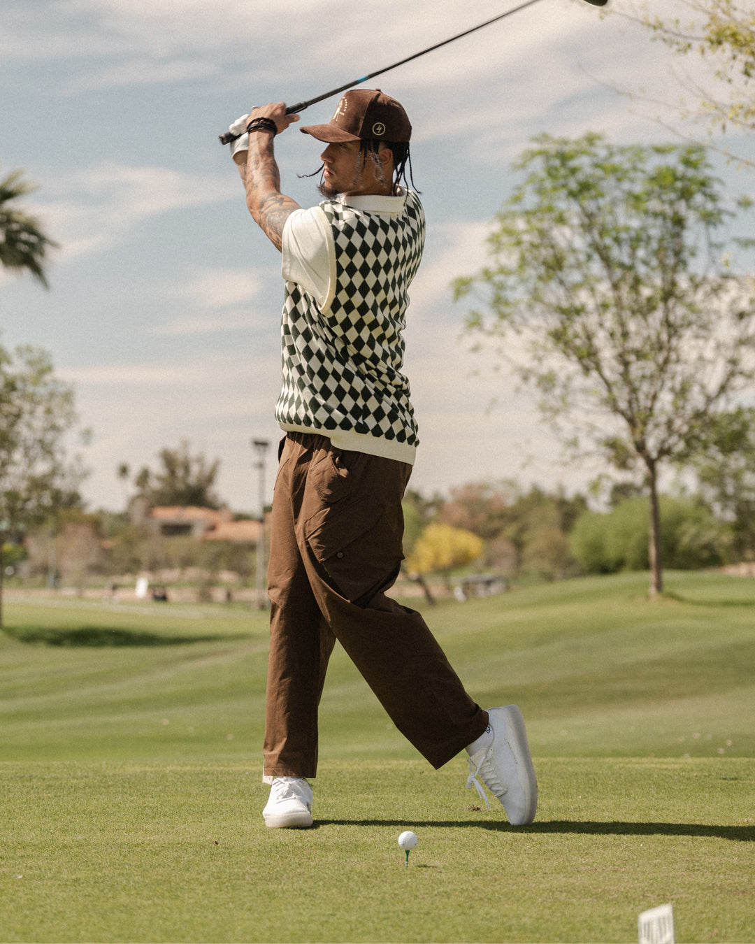 Golfer mid-swing on a course wearing white and grey Beta Lite golf shoes