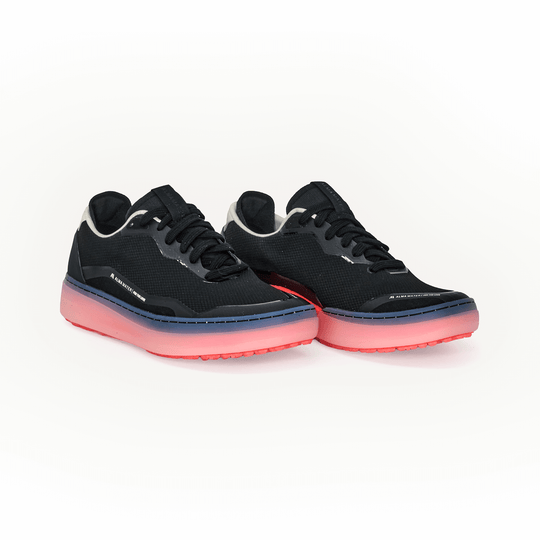 Studio image of the Men’s Beta Lite in black and flare with a breathable mesh upper, lace-up closure, and red outsole, shown as a pair at an angled front view.