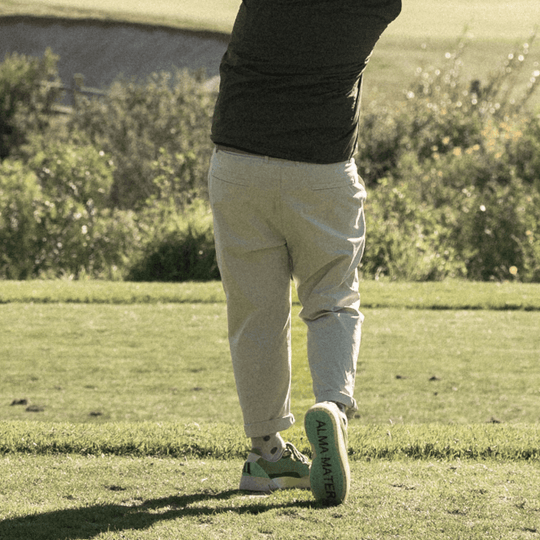 Lifestyle image of a golfer walking on the course in the Olive and Aqua Beta Lite, highlighting heel structure and outsole grip in motion.