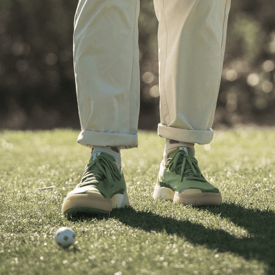 Lifestyle image of a golfer wearing the Olive and Aqua Beta Lite at address on the green, showing the shoe’s stance and traction in play.