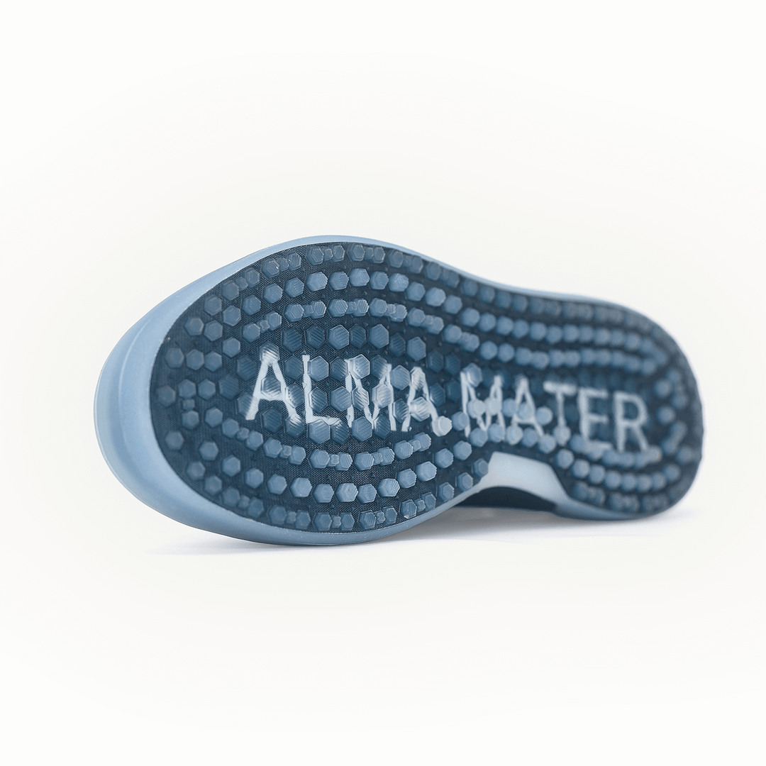 Blue Beta Longwing golf shoe shown from below, highlighting the Shark-Tooth™ Activated outsole with visible traction pattern and ALMA MATER branding across the sole.