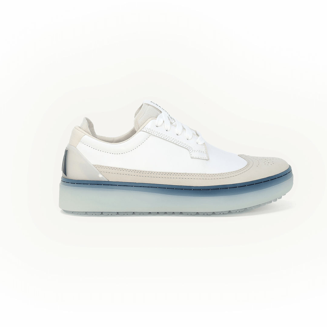 Side profile studio shot of the Beta Longwing in White and Navy, featuring a premium leather upper with classic wingtip detailing, lace-up closure, layered cupsole construction, translucent blue midsole, and spikeless outsole, set against a clean, neutral background.