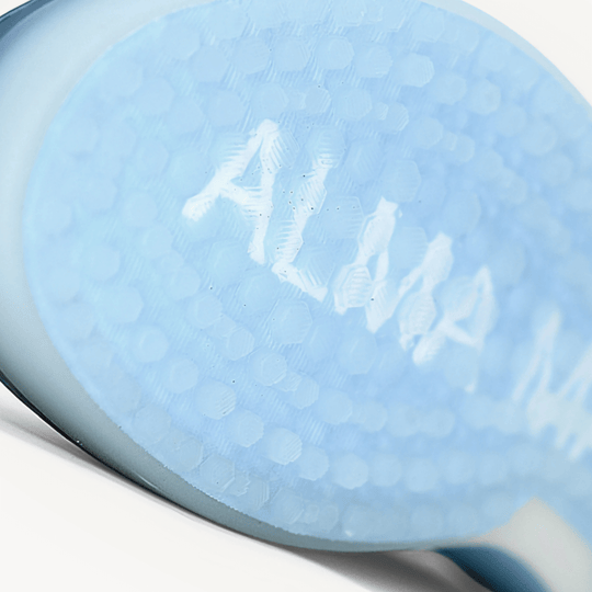 Macro close-up of the Beta Longwing White/Navy outsole, revealing the textured traction pattern and subtle ALMA MATER branding embedded within the sole.