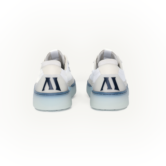 Rear studio view of the Beta Longwing in White and Navy, showing both heels side by side with molded heel counter, navy Alma Mater logo, and translucent blue cupsole construction.