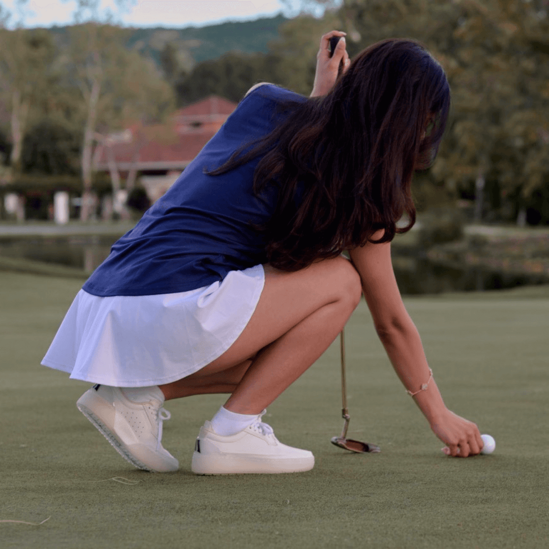 Women’s Beta Derby all-white golf shoes standing on the putting green 