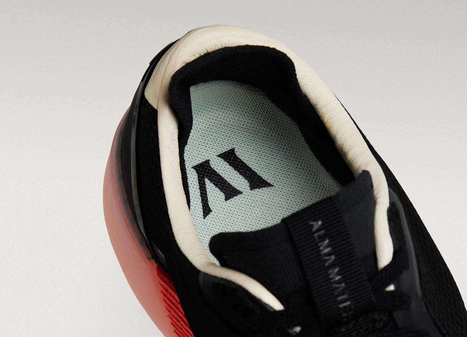 Close-up of a Beta Lite Black/ Flare with a green insole featuring a logo on a light gray background.