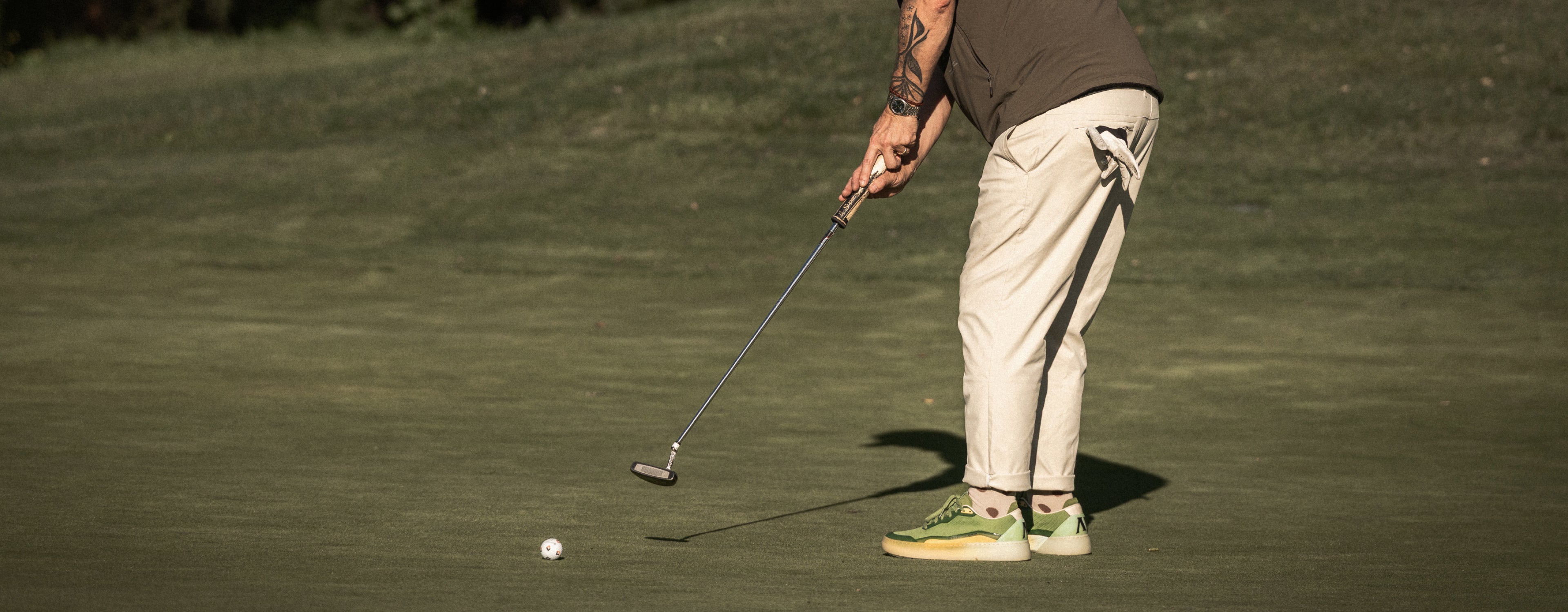 Person playing golf on a green course wearing Olive Aqua Beta Lite